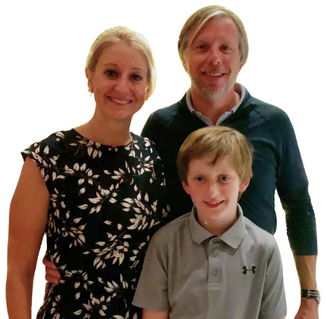 Parents and their son standing together, smiling for the photo.