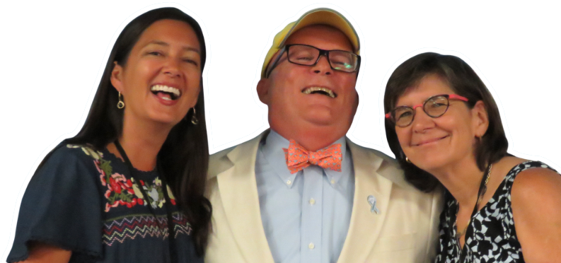 Three people smiling and laughing together in front of a light blue background.